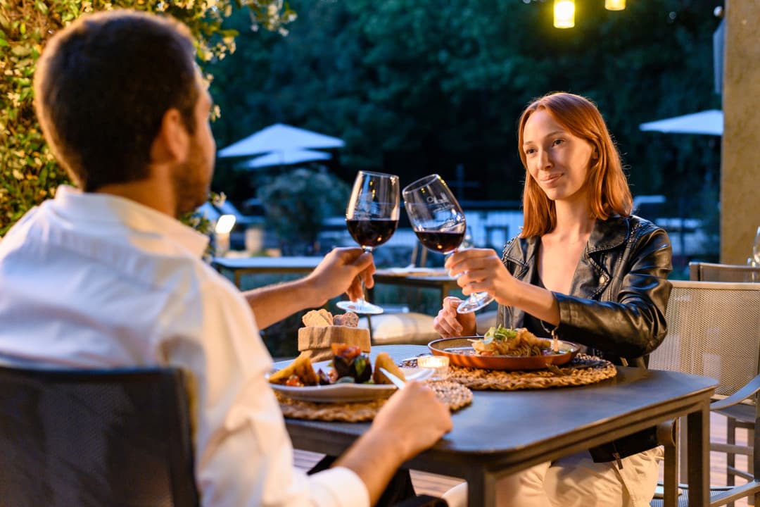 Pareja brindando con vino tinto en la terraza del restaurante