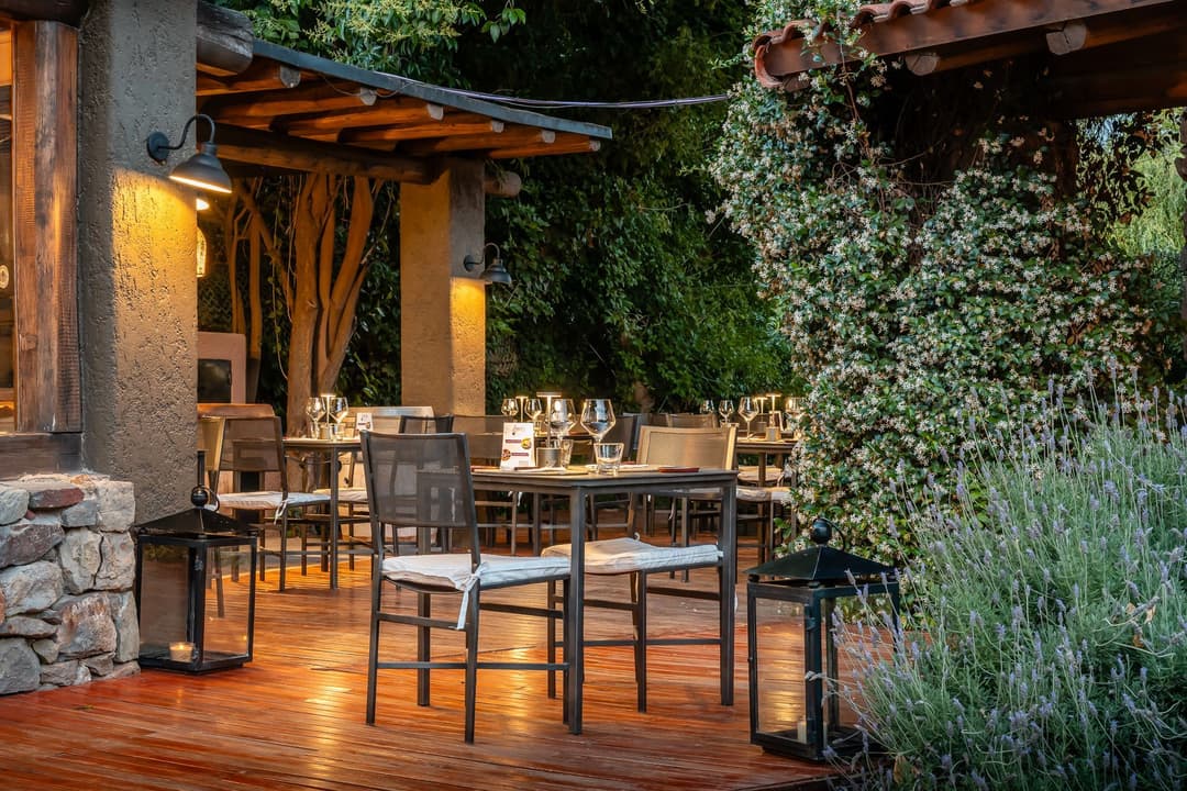 Terraza de madera con mesas, iluminada al atardecer